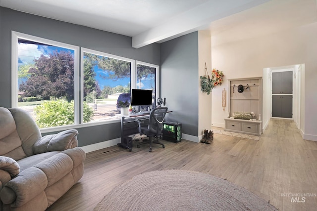 home office featuring beamed ceiling and light wood-type flooring