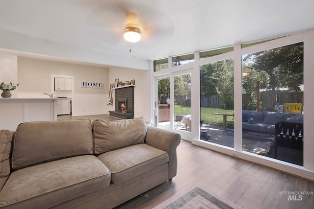 living room with hardwood / wood-style floors, ceiling fan, and a brick fireplace