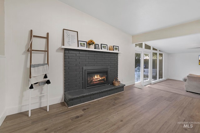 living room with hardwood / wood-style floors, a fireplace, and vaulted ceiling