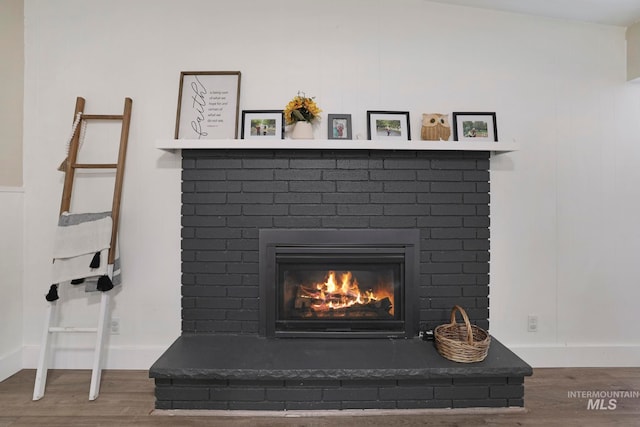 interior details featuring wood-type flooring and a brick fireplace