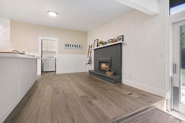 unfurnished living room with a fireplace, washer / dryer, and light hardwood / wood-style floors