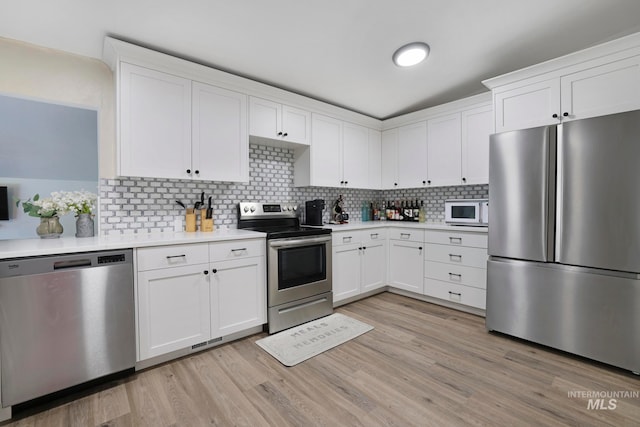 kitchen with white cabinets, backsplash, stainless steel appliances, and light hardwood / wood-style flooring