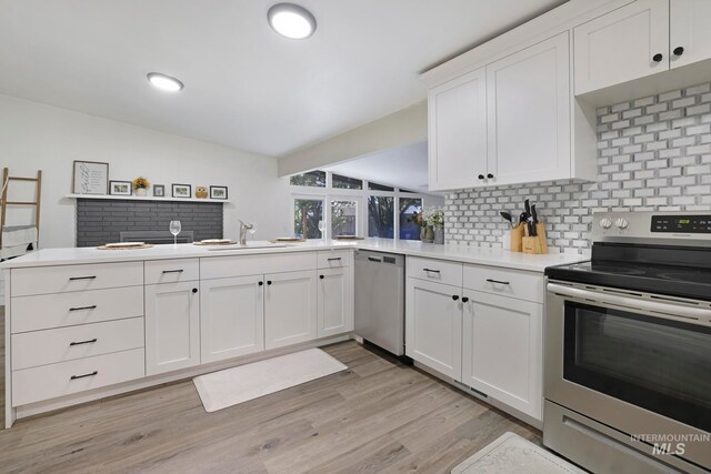 kitchen featuring sink, kitchen peninsula, decorative backsplash, appliances with stainless steel finishes, and white cabinetry