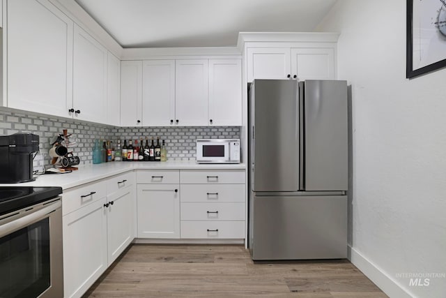 kitchen with light wood-type flooring, white cabinetry, and stainless steel appliances