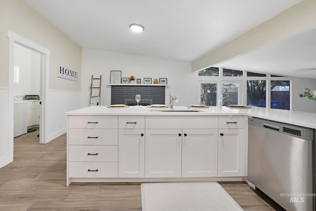 kitchen with sink, vaulted ceiling with beams, stainless steel dishwasher, white cabinets, and light wood-type flooring