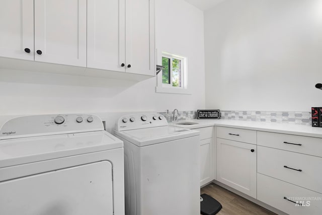 laundry room with hardwood / wood-style floors, cabinets, separate washer and dryer, and sink