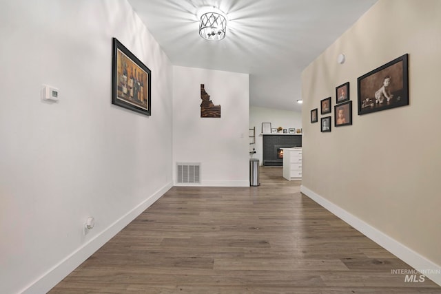 corridor with dark hardwood / wood-style flooring and lofted ceiling