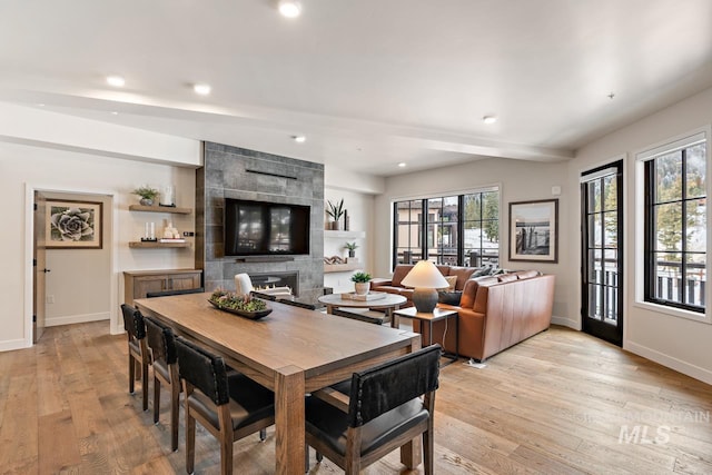 dining space featuring a fireplace, light hardwood / wood-style floors, and beam ceiling