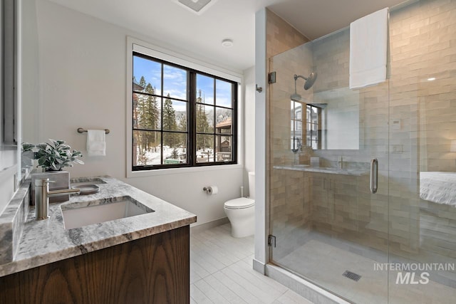 bathroom featuring vanity, a shower with shower door, and toilet