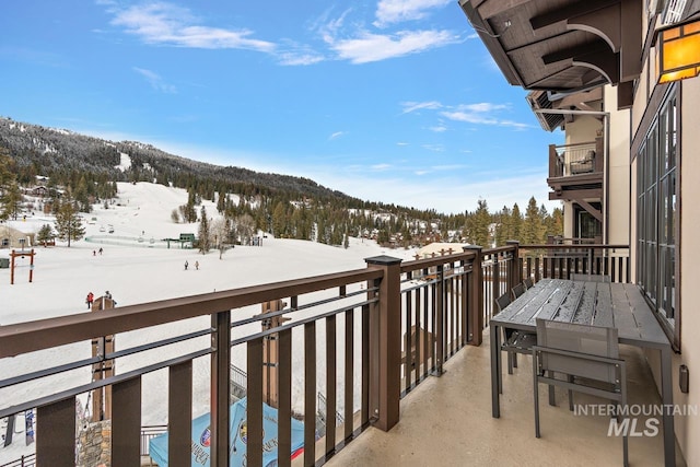 snow covered back of property with a mountain view