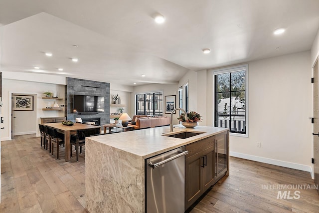 kitchen featuring dishwasher, a kitchen island with sink, sink, and light hardwood / wood-style floors