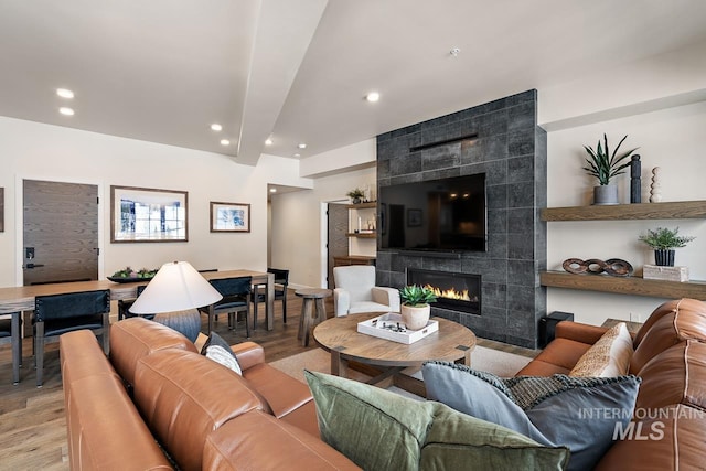 living room featuring light hardwood / wood-style flooring, a fireplace, and beamed ceiling