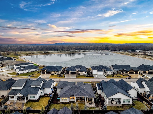 aerial view at dusk with a residential view and a water view