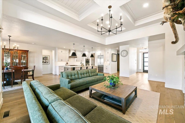 living area featuring coffered ceiling, visible vents, light wood finished floors, an inviting chandelier, and crown molding