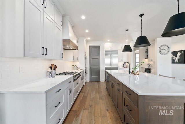 kitchen with light countertops, a sink, custom exhaust hood, and white cabinetry