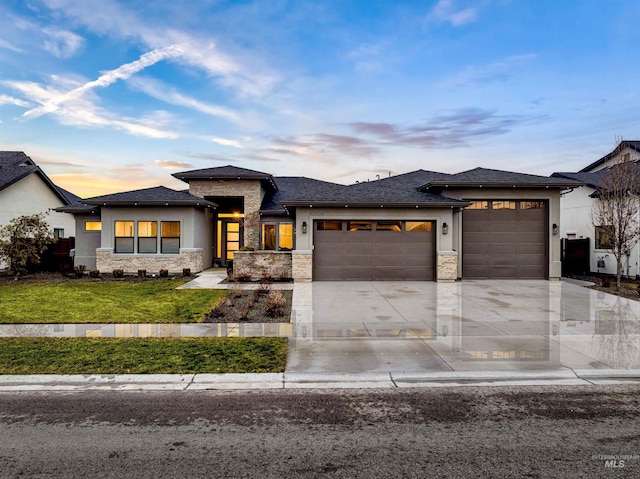 prairie-style house featuring a garage, stone siding, and stucco siding