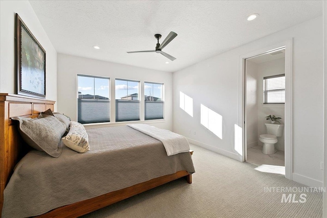 bedroom with light colored carpet, a textured ceiling, and baseboards