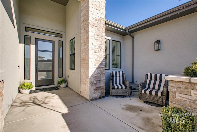 doorway to property with stone siding, a porch, and stucco siding