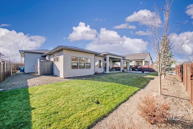 back of house with a patio, a lawn, a fenced backyard, and stucco siding