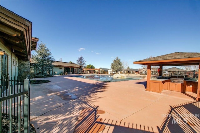 community pool with an outdoor kitchen, a patio, and area for grilling