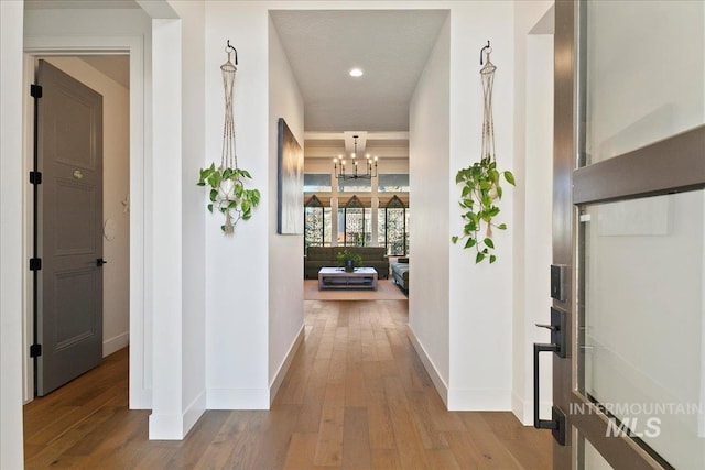 hallway with a notable chandelier, recessed lighting, wood finished floors, and baseboards