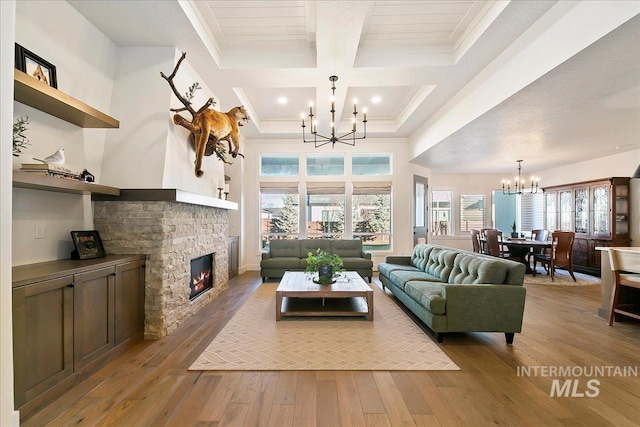 living area with a fireplace, ornamental molding, a chandelier, beamed ceiling, and hardwood / wood-style floors