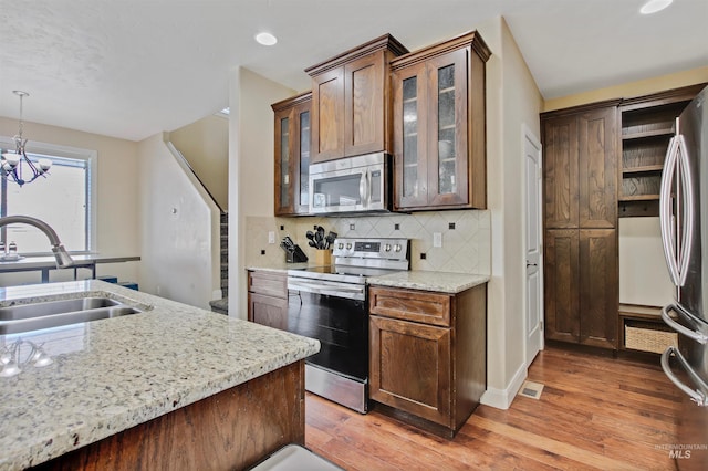 kitchen featuring decorative backsplash, stainless steel appliances, sink, pendant lighting, and a chandelier