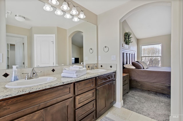 bathroom featuring tile patterned flooring, vanity, and vaulted ceiling