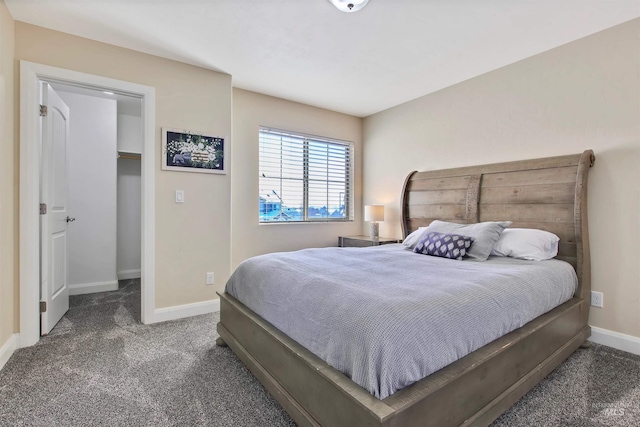 bedroom with dark colored carpet and a walk in closet