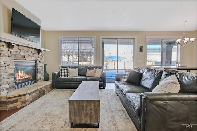 living room featuring a stone fireplace and an inviting chandelier