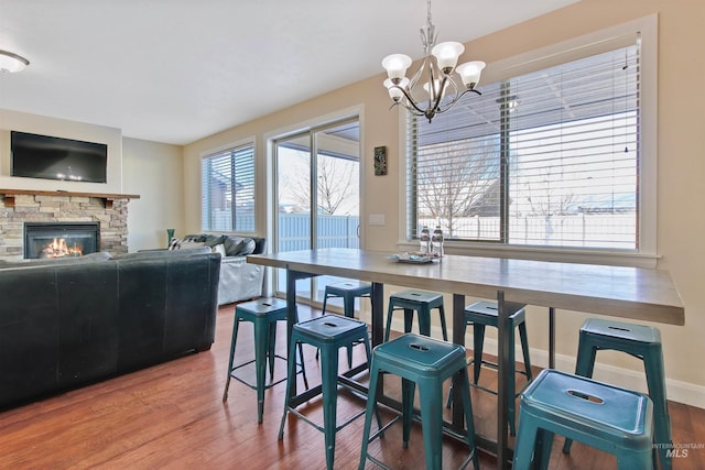 dining area with a fireplace, hardwood / wood-style floors, and an inviting chandelier