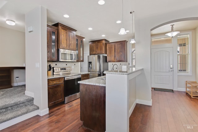 kitchen featuring light stone countertops, sink, tasteful backsplash, pendant lighting, and appliances with stainless steel finishes