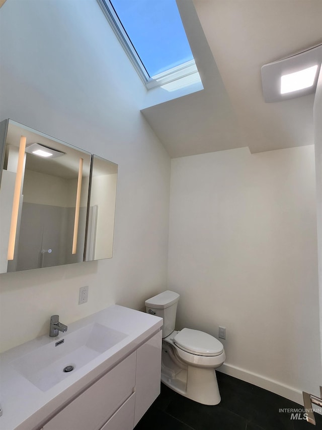 bathroom featuring a skylight, vanity, toilet, and baseboards