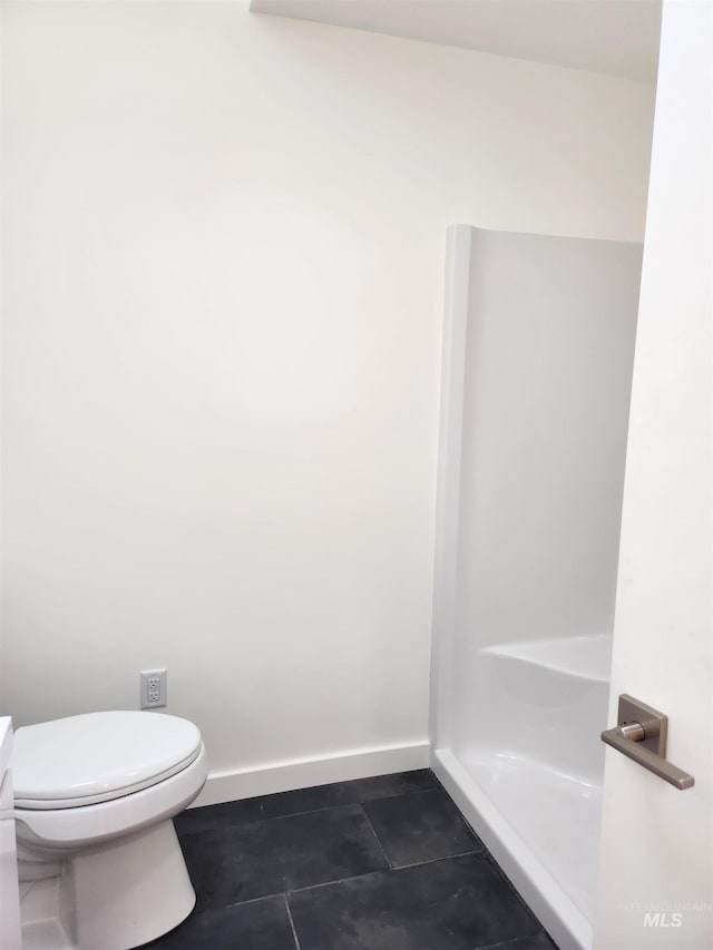 bathroom featuring toilet, tile patterned flooring, baseboards, and walk in shower