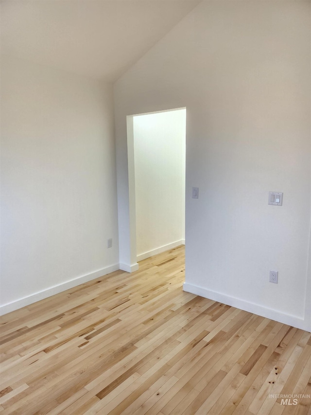 unfurnished room with light wood-style flooring, baseboards, and vaulted ceiling