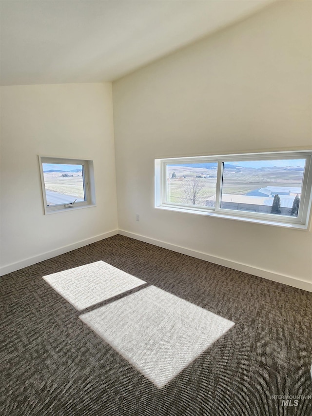 spare room with dark colored carpet and baseboards