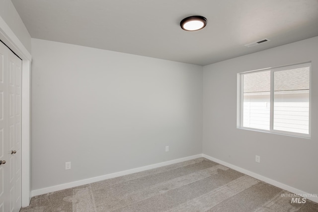 carpeted empty room featuring visible vents and baseboards