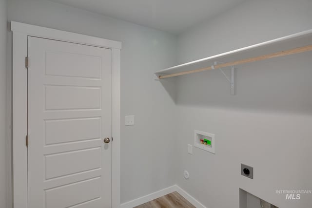 clothes washing area with laundry area, light wood-style flooring, electric dryer hookup, washer hookup, and baseboards
