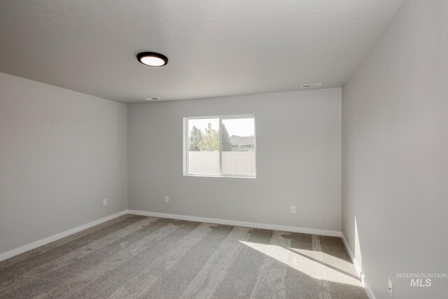 carpeted spare room with baseboards and visible vents