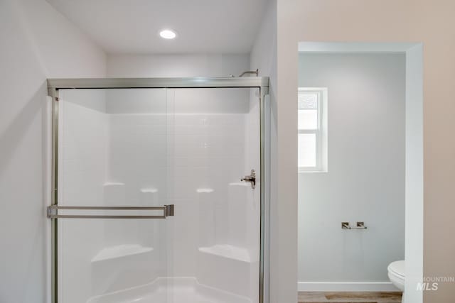 full bathroom with toilet, baseboards, and a shower stall
