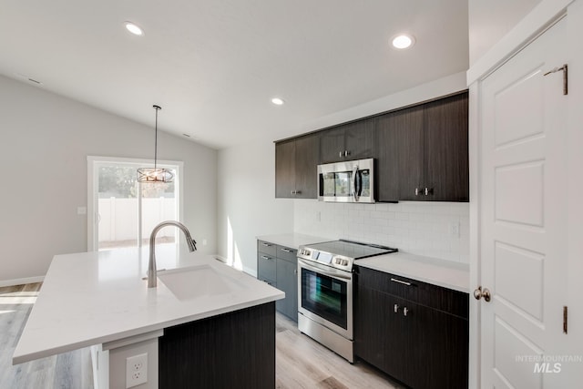kitchen featuring a sink, lofted ceiling, light wood-style flooring, backsplash, and appliances with stainless steel finishes