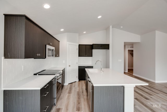 kitchen with light wood-style flooring, stainless steel appliances, a sink, light countertops, and tasteful backsplash