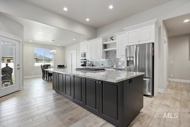 kitchen featuring light hardwood / wood-style floors, white cabinetry, a spacious island, and appliances with stainless steel finishes