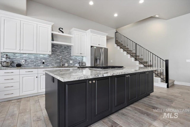 kitchen with white cabinetry, a center island, light stone countertops, and appliances with stainless steel finishes