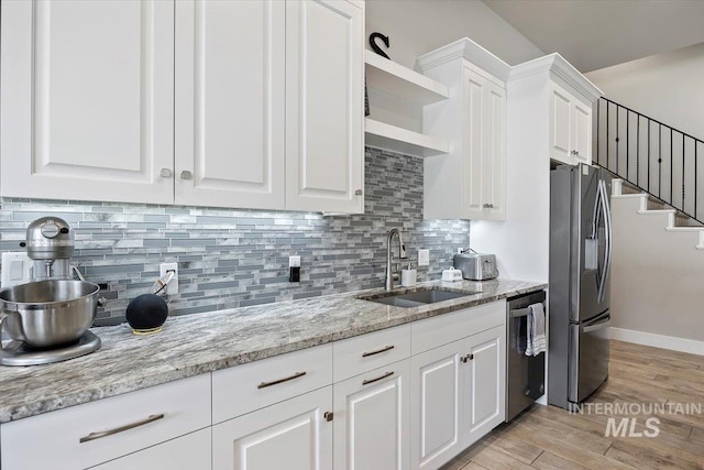 kitchen featuring light stone countertops, white cabinetry, sink, stainless steel appliances, and light hardwood / wood-style floors