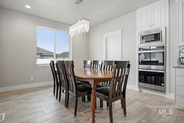 dining space featuring light hardwood / wood-style flooring and a notable chandelier