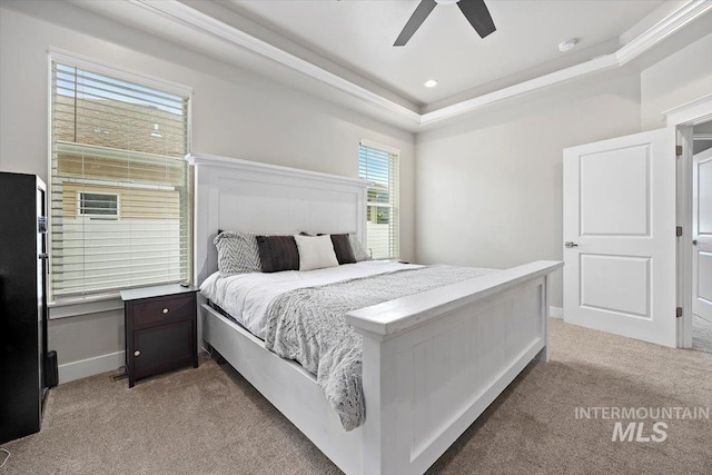 bedroom featuring light colored carpet, a raised ceiling, and ceiling fan