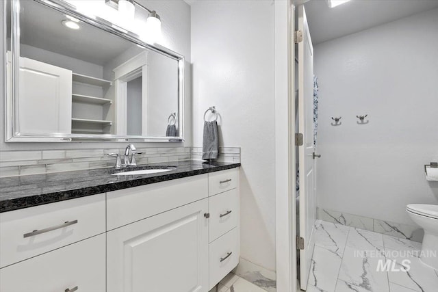 bathroom featuring tasteful backsplash, vanity, and toilet