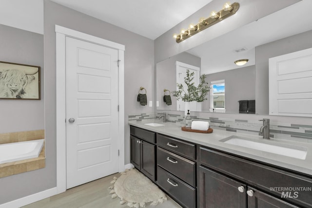 12041 W Ardyce, Boise, ID 83713 - bathroom with double vanity, decorative backsplash, a bath, wood finished floors, and baseboards