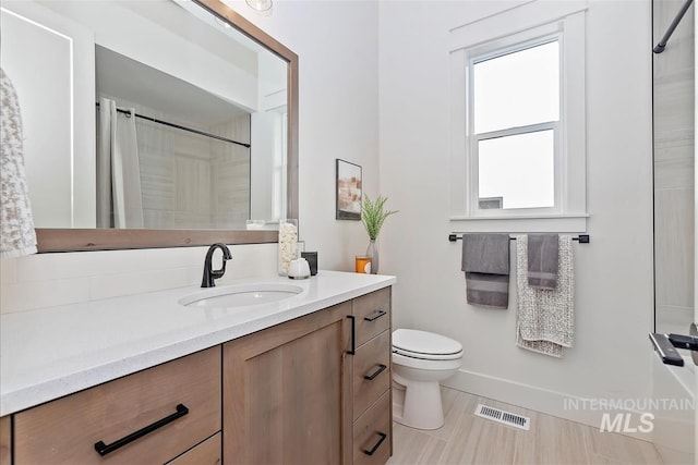 bathroom featuring vanity, toilet, and walk in shower